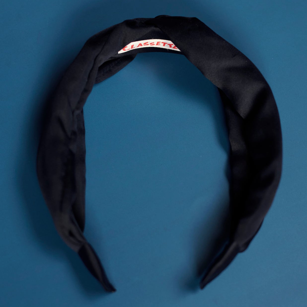 Navy headband with a Classette label on a blue background